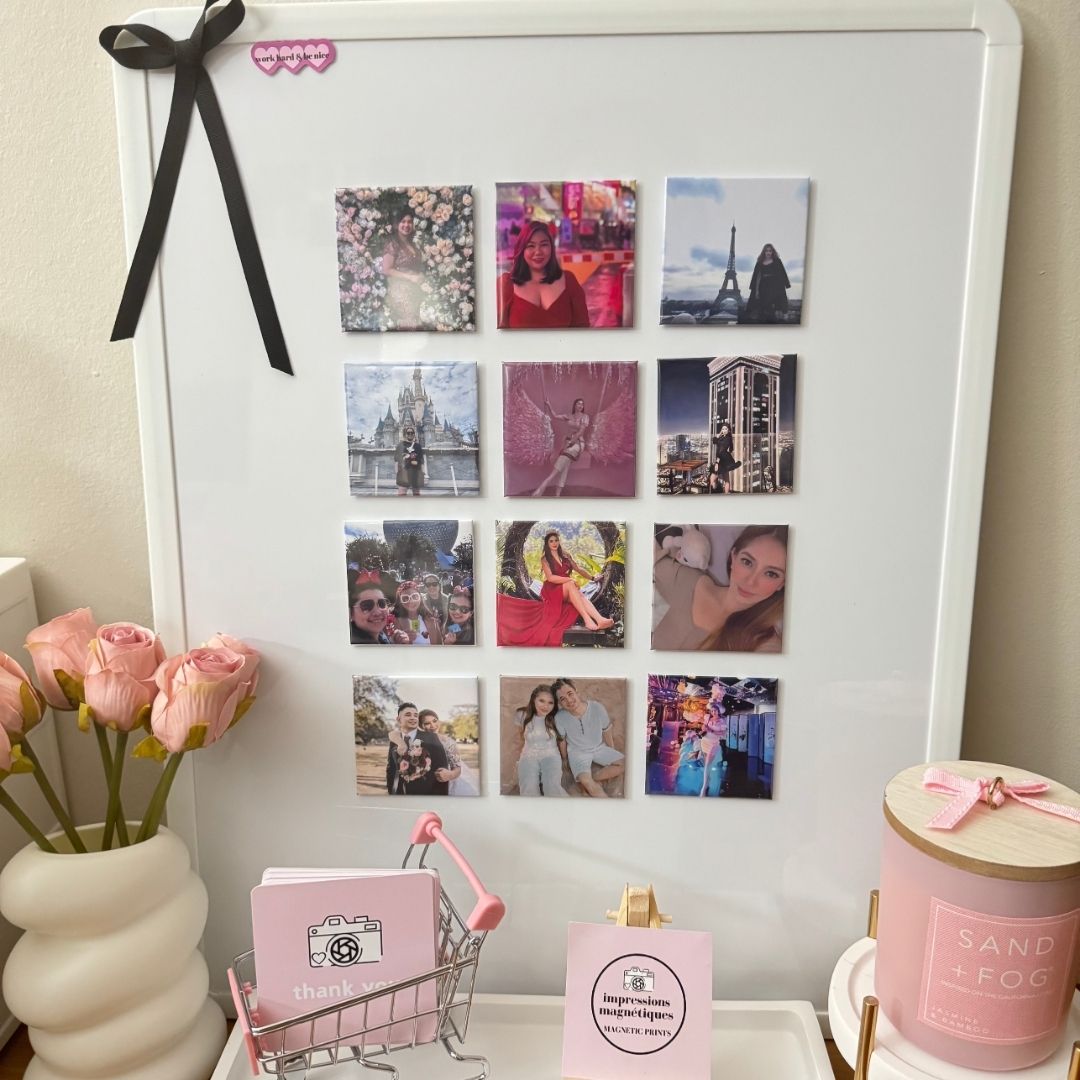 A whiteboard decorated with 12 square photo magnets arranged in a grid, surrounded by pink roses, a candle, and thank-you cards.